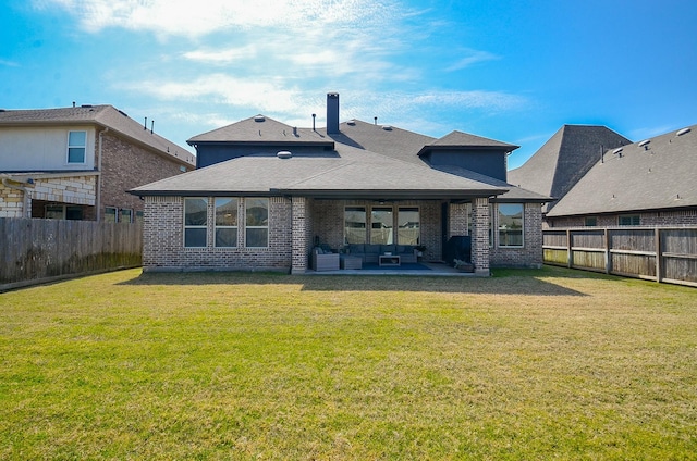 rear view of house featuring a patio area, a yard, a fenced backyard, and brick siding