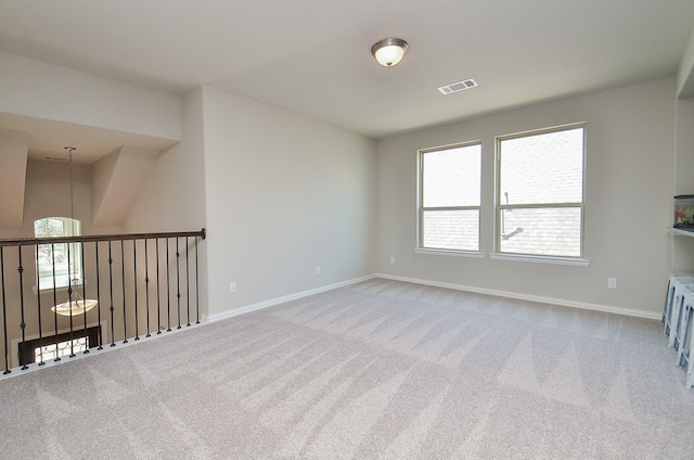 spare room with baseboards, visible vents, and light colored carpet