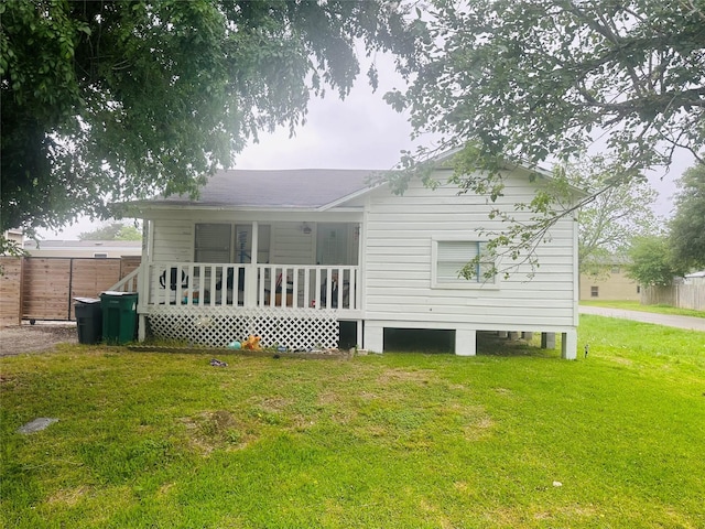 back of house featuring fence and a lawn