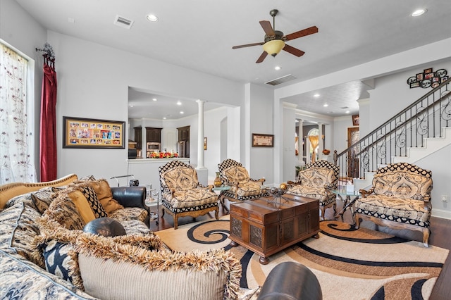 living room featuring ornate columns, stairway, visible vents, and a ceiling fan