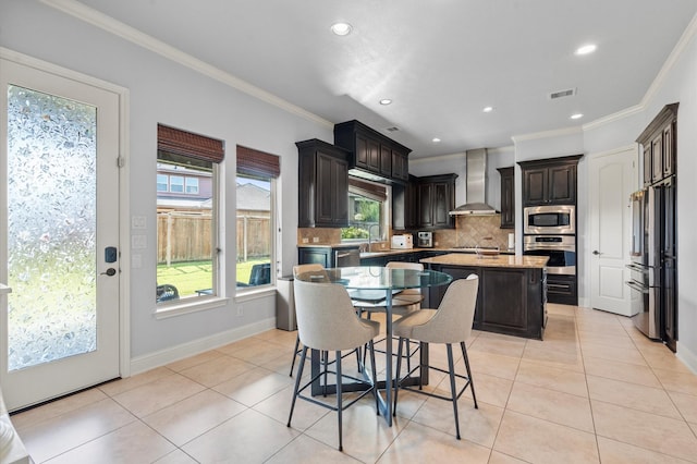 kitchen with light tile patterned floors, stainless steel appliances, wall chimney range hood, and visible vents