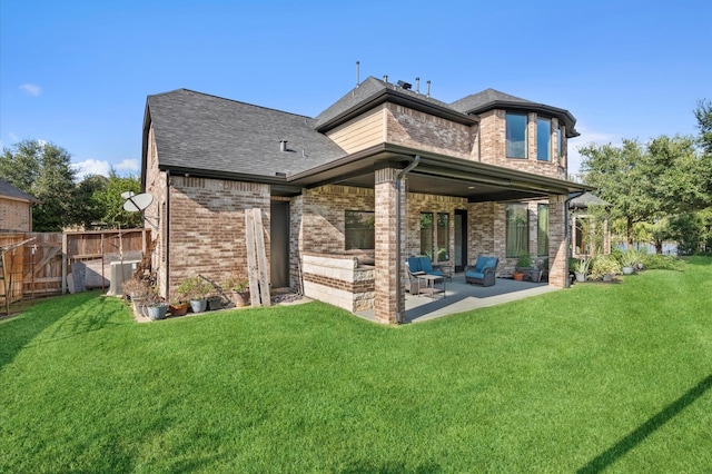 rear view of house with a patio, roof with shingles, fence, a yard, and brick siding