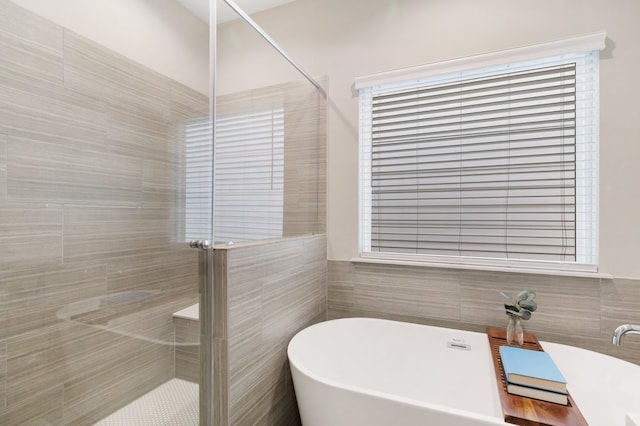 full bath with a freestanding bath, a shower stall, and tile walls