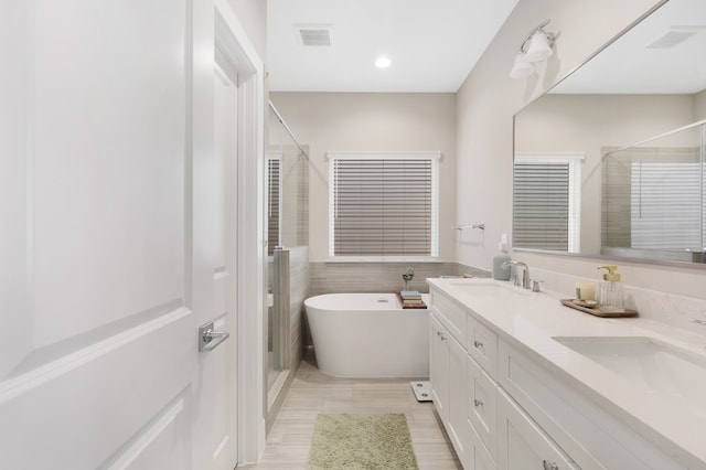 bathroom with a stall shower, a freestanding tub, and a sink