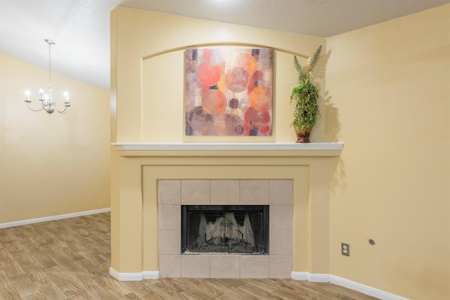 interior details featuring a fireplace, wood finished floors, an inviting chandelier, and baseboards