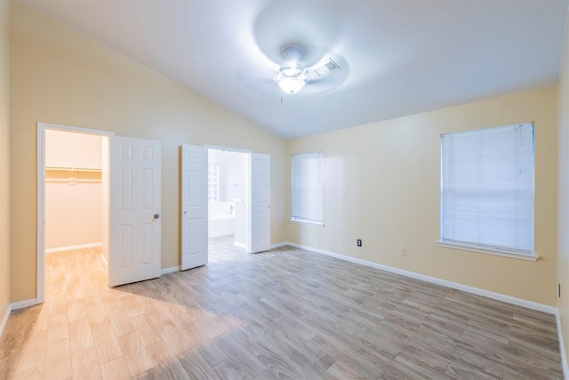 unfurnished room with ceiling fan, light wood-style flooring, baseboards, and vaulted ceiling