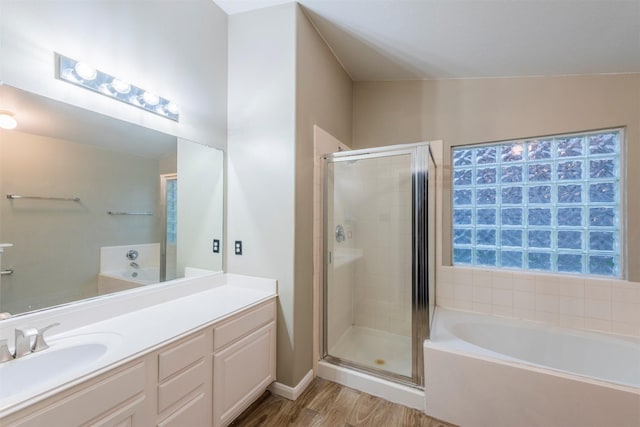 bathroom with wood finished floors, a stall shower, a garden tub, and vanity