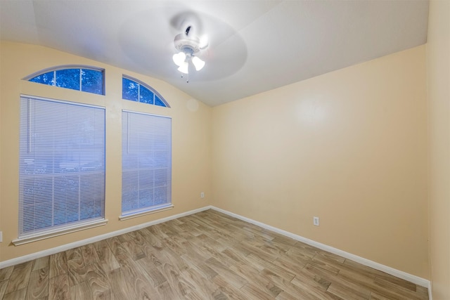 spare room featuring a ceiling fan, lofted ceiling, baseboards, and light wood finished floors