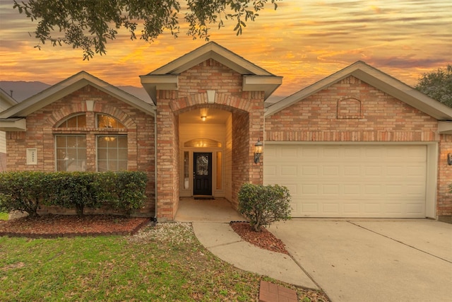 view of front of home with a garage, concrete driveway, and brick siding