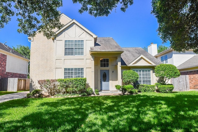 traditional-style home featuring brick siding, fence, stucco siding, and a front yard