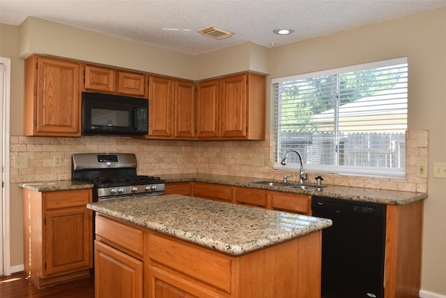 kitchen featuring light stone counters, visible vents, decorative backsplash, a sink, and black appliances