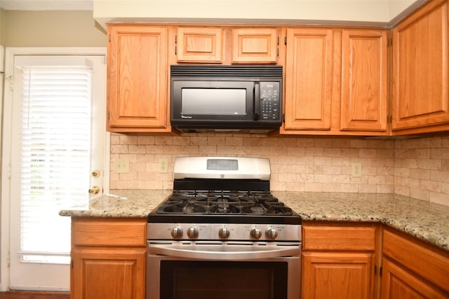 kitchen with tasteful backsplash, black microwave, light stone counters, and gas stove