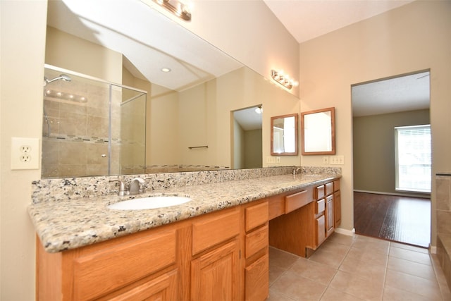 full bath featuring a stall shower, double vanity, a sink, and tile patterned floors