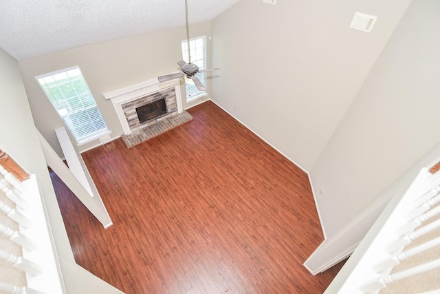 living area featuring a textured ceiling, wood finished floors, plenty of natural light, and a glass covered fireplace