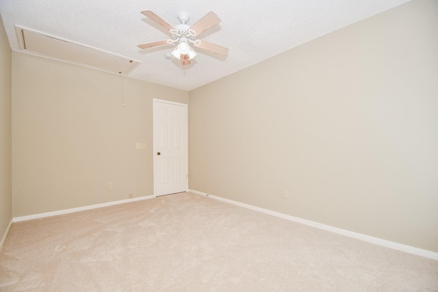 unfurnished room with a textured ceiling, light carpet, a ceiling fan, baseboards, and attic access