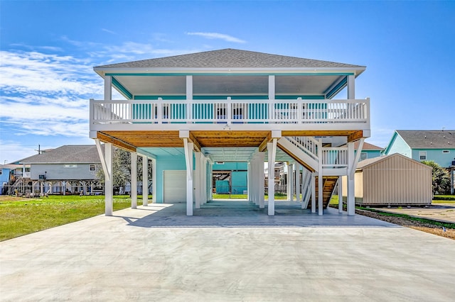 view of front of property with a shingled roof, covered porch, stairway, a garage, and a carport