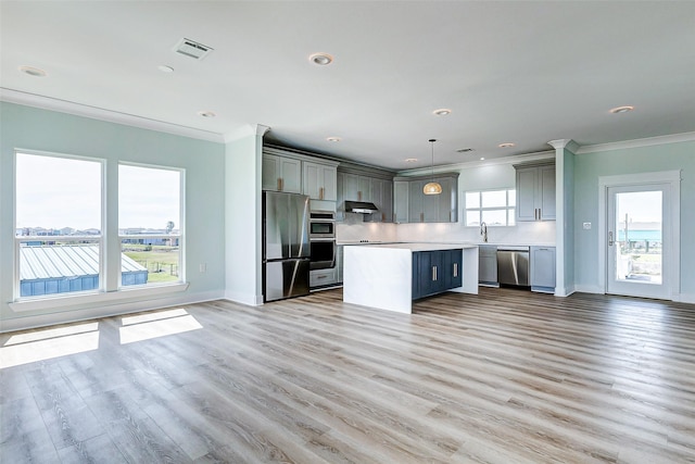 kitchen with ornamental molding, gray cabinets, stainless steel appliances, light countertops, and under cabinet range hood