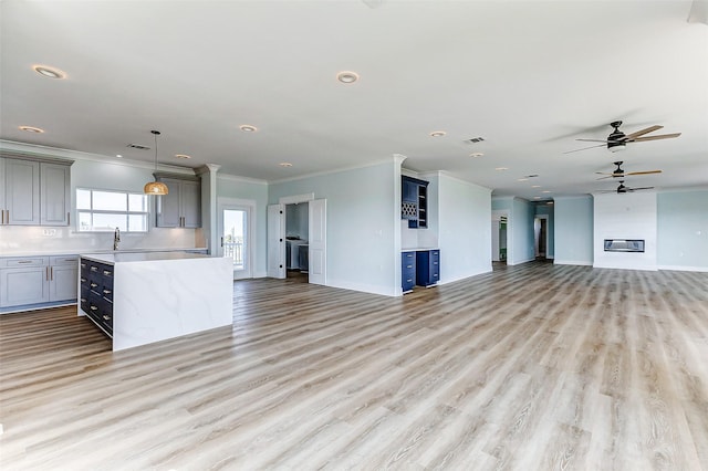 unfurnished living room featuring light wood-style flooring, crown molding, visible vents, and baseboards