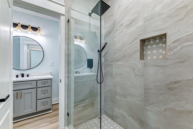 bathroom with wood finished floors, vanity, and a walk in shower