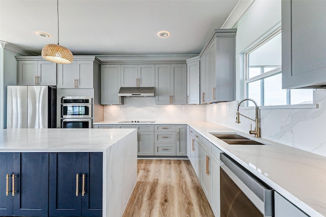 kitchen with under cabinet range hood, tasteful backsplash, stainless steel appliances, and a sink