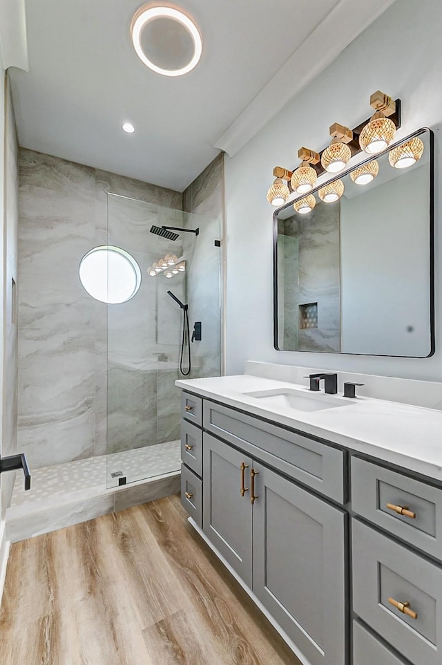 full bath featuring a walk in shower, wood finished floors, and vanity