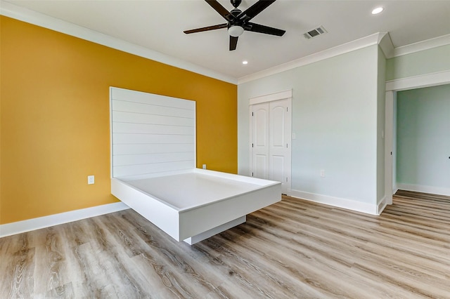 interior space featuring baseboards, wood finished floors, visible vents, and crown molding