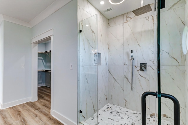 bathroom featuring a spacious closet, wood finished floors, a marble finish shower, and visible vents