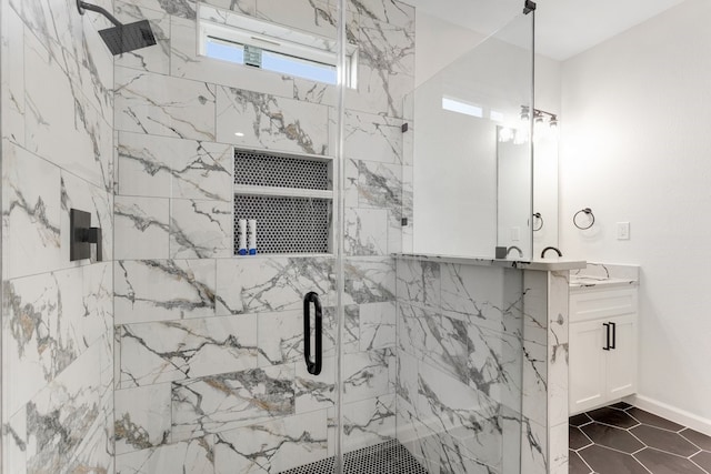 full bath featuring vanity, baseboards, and a marble finish shower