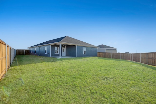 rear view of property featuring ceiling fan, a lawn, a fenced backyard, and a patio area