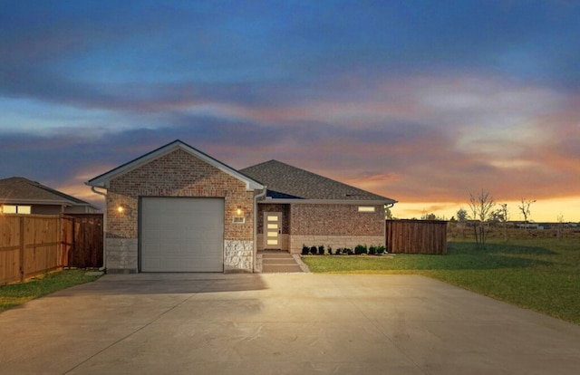 ranch-style house featuring an attached garage, concrete driveway, a yard, and fence