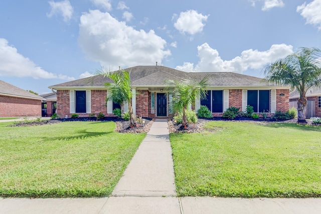 ranch-style house featuring a front yard, brick siding, and roof with shingles