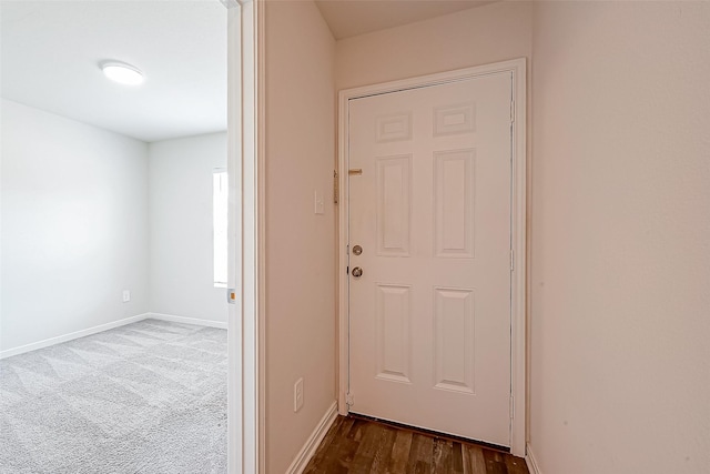 doorway featuring dark colored carpet and baseboards