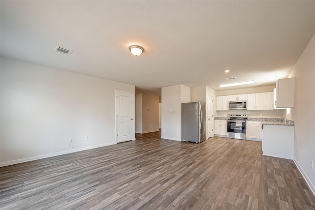 kitchen featuring stainless steel appliances, visible vents, baseboards, open floor plan, and dark wood finished floors