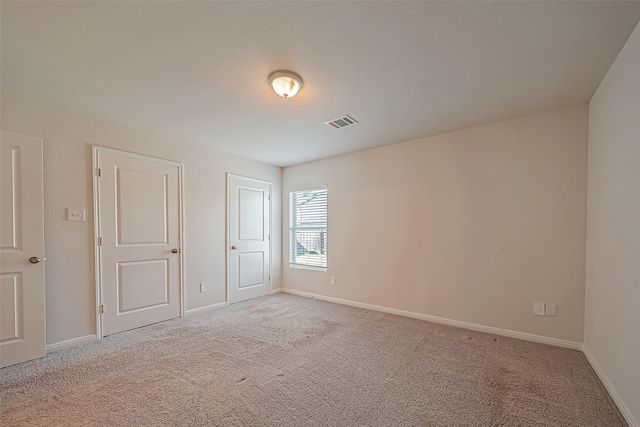 unfurnished bedroom with baseboards, visible vents, and light colored carpet