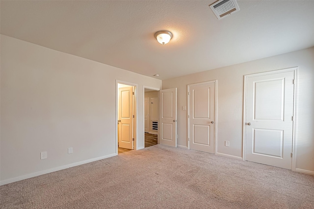 unfurnished bedroom with carpet, visible vents, and baseboards