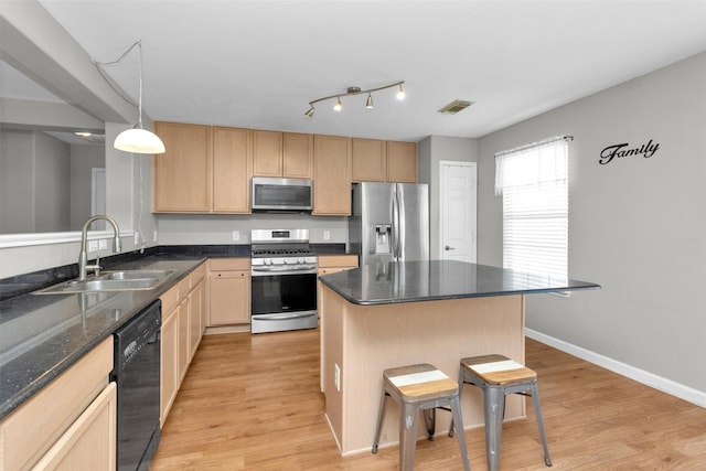 kitchen with light wood finished floors, stainless steel appliances, visible vents, light brown cabinetry, and a sink