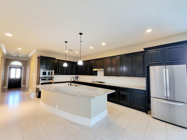 kitchen featuring decorative backsplash, light stone countertops, stainless steel appliances, under cabinet range hood, and a sink