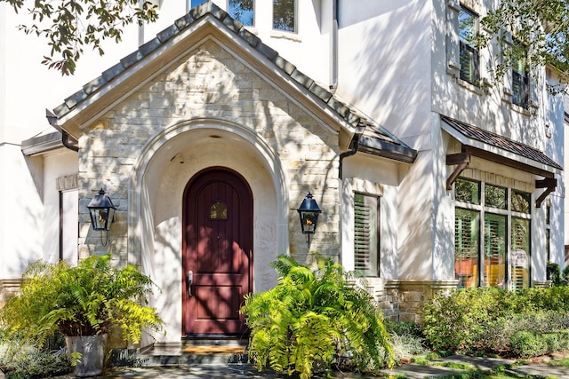 entrance to property featuring stone siding and stucco siding