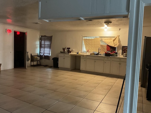 kitchen featuring a sink, light tile patterned floors, light countertops, and a textured ceiling