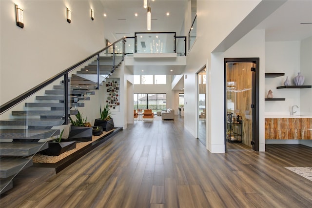 entryway featuring stairs, a high ceiling, wet bar, and wood finished floors