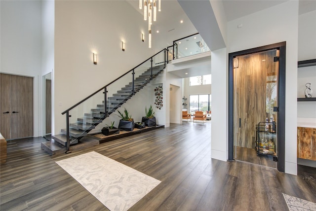 foyer with stairs, a towering ceiling, and wood finished floors