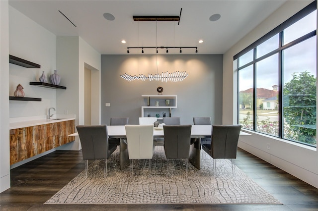 dining room with dark wood-style floors, wet bar, and rail lighting