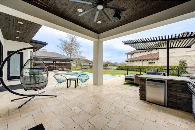 view of patio featuring ceiling fan, exterior kitchen, fence, and a fenced in pool