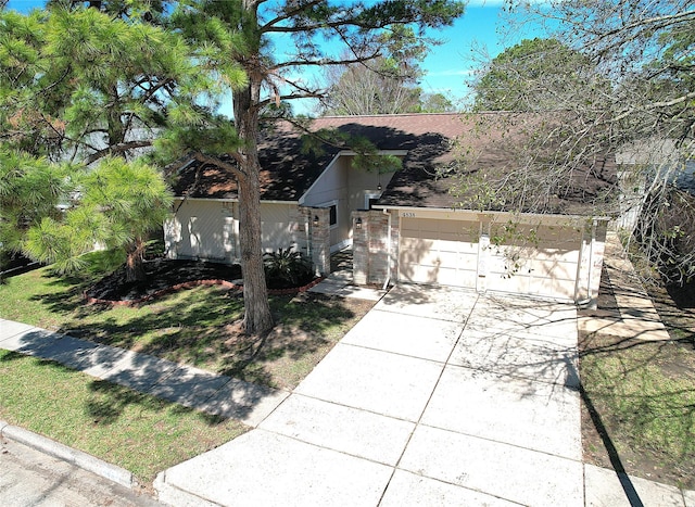 view of front facade with a garage, driveway, and a shingled roof