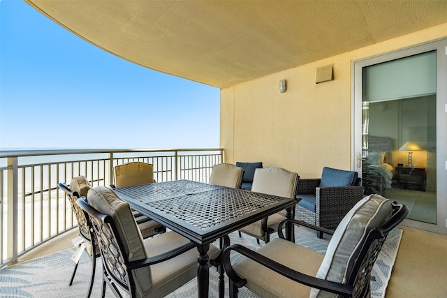 balcony featuring a water view and outdoor dining area