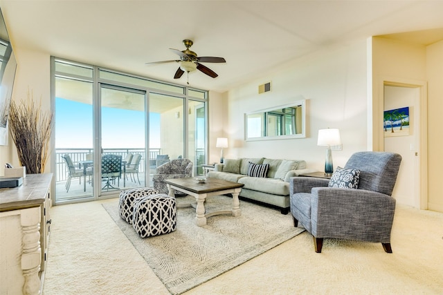 living room with expansive windows, carpet floors, visible vents, and a ceiling fan