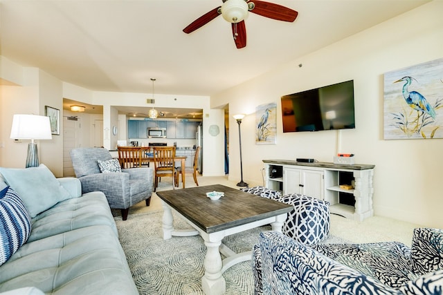 living room with baseboards, a ceiling fan, and light colored carpet