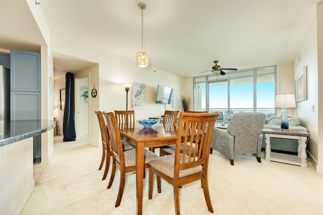 dining space with a wall of windows, light carpet, and ceiling fan