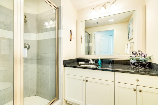 bathroom featuring toilet, vanity, a shower stall, and visible vents