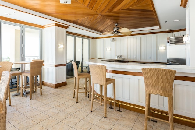 kitchen with light tile patterned floors, wood ceiling, a ceiling fan, fridge, and a raised ceiling